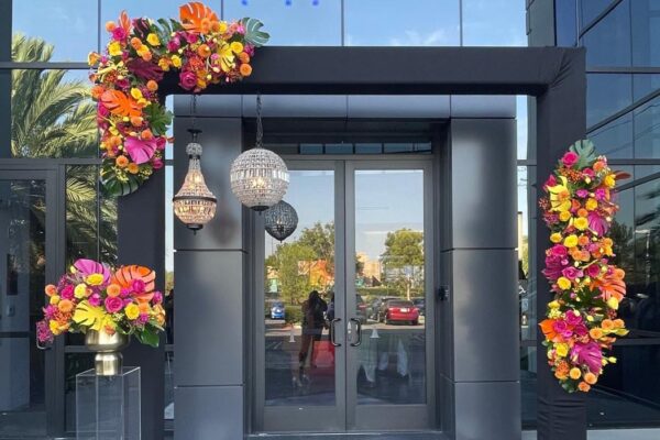 Black truss entrance arch with tropical florals and hanging crystal pendant lights