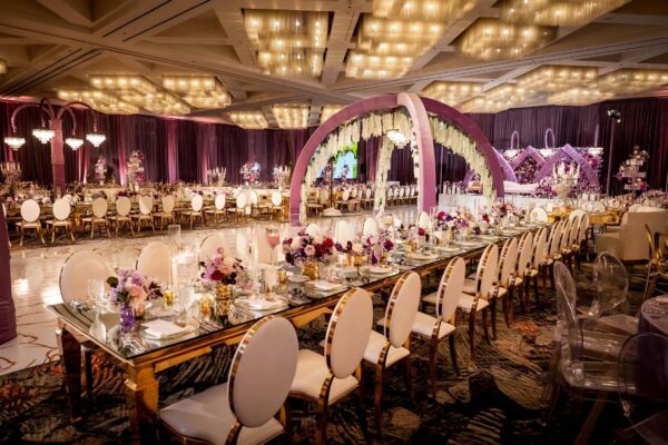 Lavender velvet arches draped with white wisteria over a patterned dance floor in a ballroom